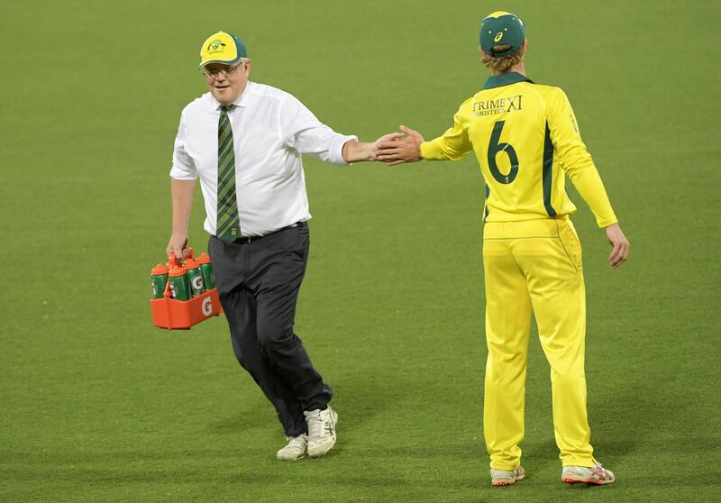 Australia PM Scott Morrison carries drinks during the tour match at the Manuka Oval. Getty Images