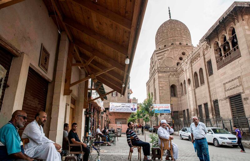 Men sit at a cafe by the 15th century Sultan Qaitbay mosque complex in the "Desert of the Mamluks" (City of the Dead) area of Egypt's capital Cairo on November 1, 2020. In Egypt's "City of the Dead", centuries-old monuments are being restored and artisanal heritage revived, turning a corner of the vast historical cemetery into a vibrant neighbourhood full of life. Since 2014, a series of projects financed by the European Union has changed the face of this small section of the sprawling necropolis -- home to many people who are unable to afford Cairo's prohibitively high rents. / AFP / Khaled DESOUKI
