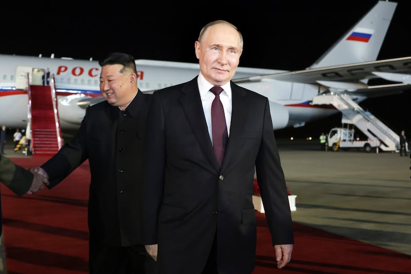 Mr Putin walks ahead as Mr Kim shakes hands with members of the Russian delegation. AP / Kremin pool