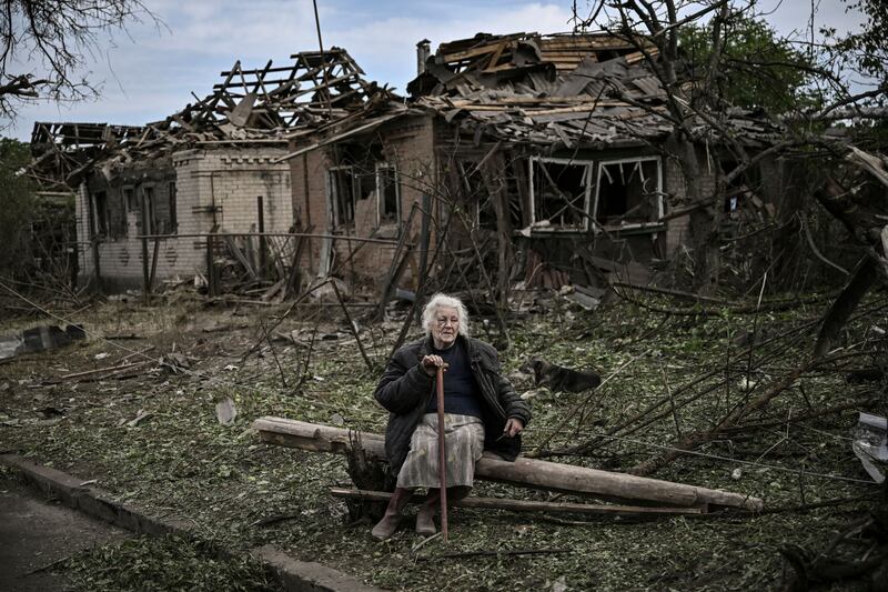 An elderly woman sits in front of destroyed houses after a missile strike, which killed a civilian, in the city of Druzhkivka in the eastern Ukrainian region of Donbas. AFP
