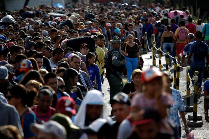 FILE PHOTO: A Venezuelan National Guard stands next to people queueing to try to cross into Colombia from Venezuela through Simon Bolivar international bridge in San Antonio del Tachira, Venezuela January 24, 2018. REUTERS/Carlos Garcia Rawlins/File Photo