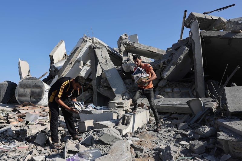 Palestinians collect books from the rubble of a cultural centre following an Israeli strike in Rafah. AFP