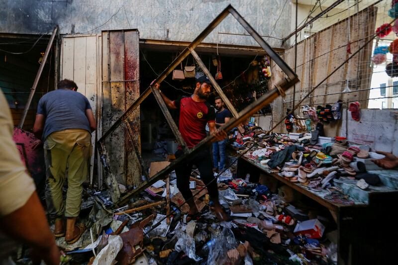 People pick up debris at the site of an explosion in the Sadr City district of Baghdad.
