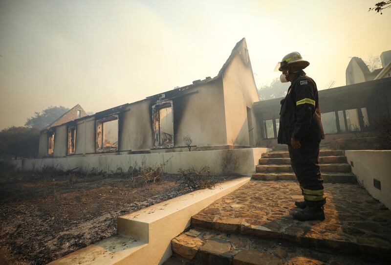 A firefighter surveys the smouldering shells of buildings at the historic Mostert's Mill site, destroyed in the bushfire on the slopes of Table Mountain, Cape Town. Reuters