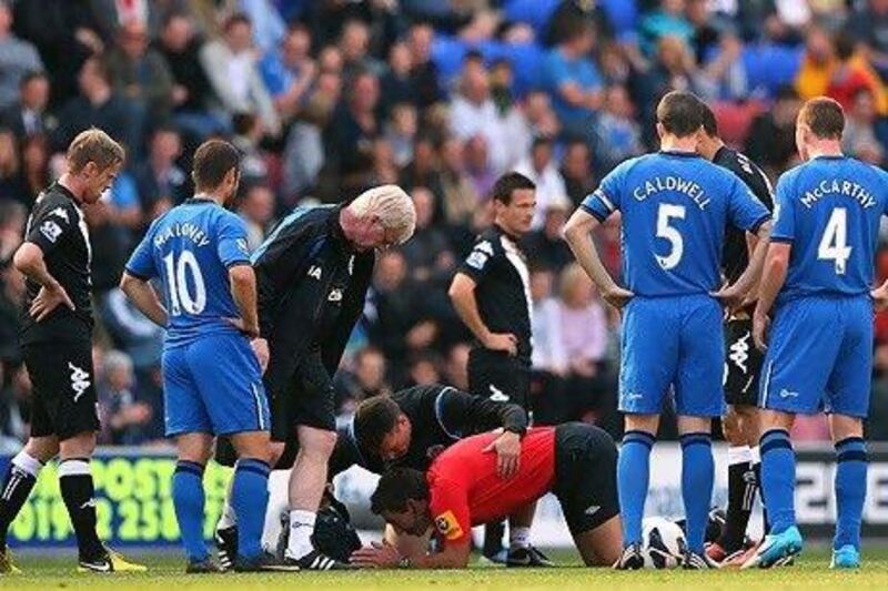 Lee Probert, the referee, centre, was knocked down during the clash between Wigan Athletic and Fulham.