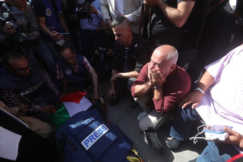 Palestinian journalists mourn near Abu Akleh's body. EPA