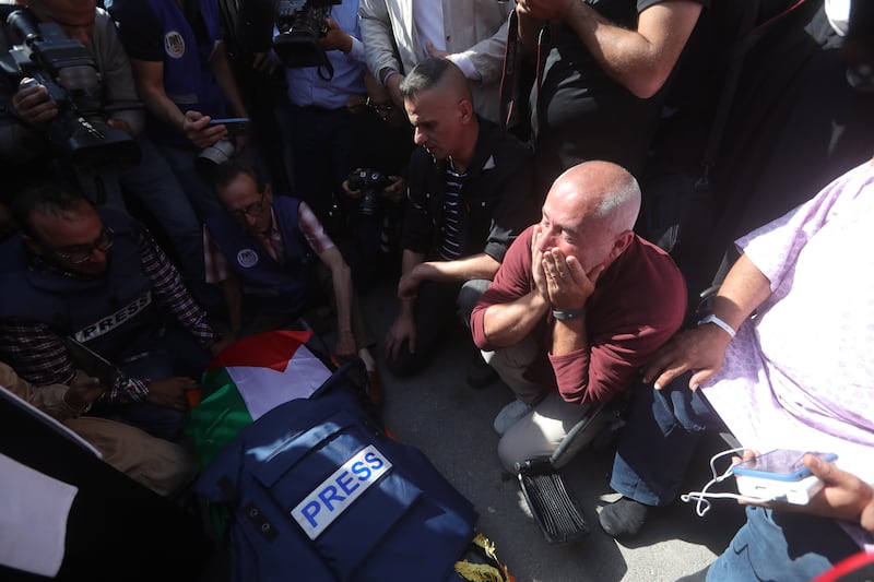 Palestinian journalists mourn near Abu Akleh's body. EPA