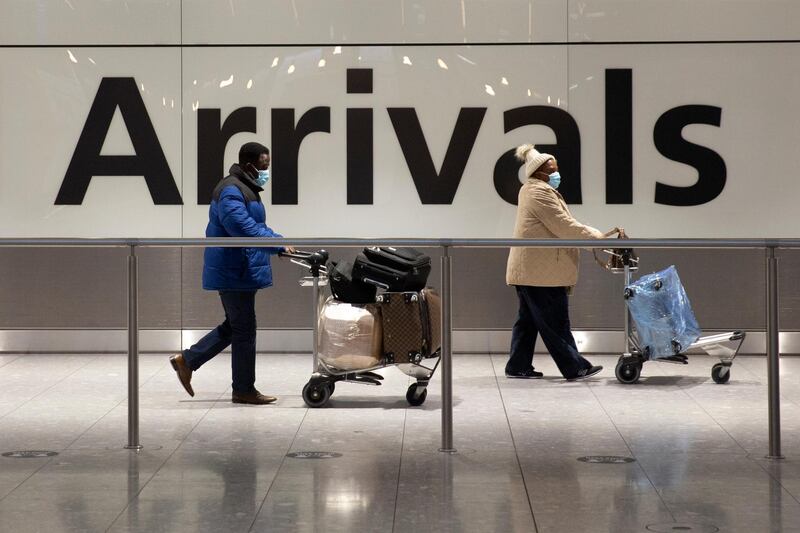 Arriving passengers walk past a sign in the arrivals area at Heathrow Airport in London, Tuesday, Jan. 26, 2021, during England's third national lockdown since the coronavirus outbreak began. The British government are on Tuesday expected to discuss whether to force some travellers arriving in the UK to quarantine in hotels to try to curb the spread of coronavirus. (AP Photo/Matt Dunham)