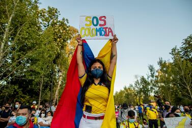 A woman holds a banner during a protest against the violence happening in Colombia over tax reform in Madrid, Spain. AP