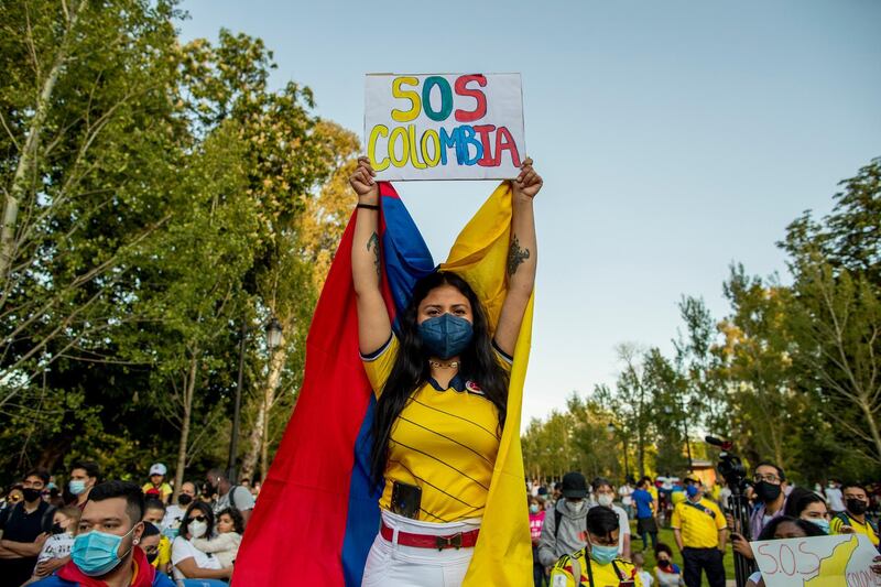 A woman holds a banner reading: "SOS Colombia" during a protest against the violence happening in Colombia against tax reform in Madrid, Spain, Thursday, May 6, 2021. The demonstration is in support of protests that began last week over a tax reform proposal that continue despite Colombia's President Ivan Duque's withdrawal of the tax plan. (AP Photo/Manu Fernandez)