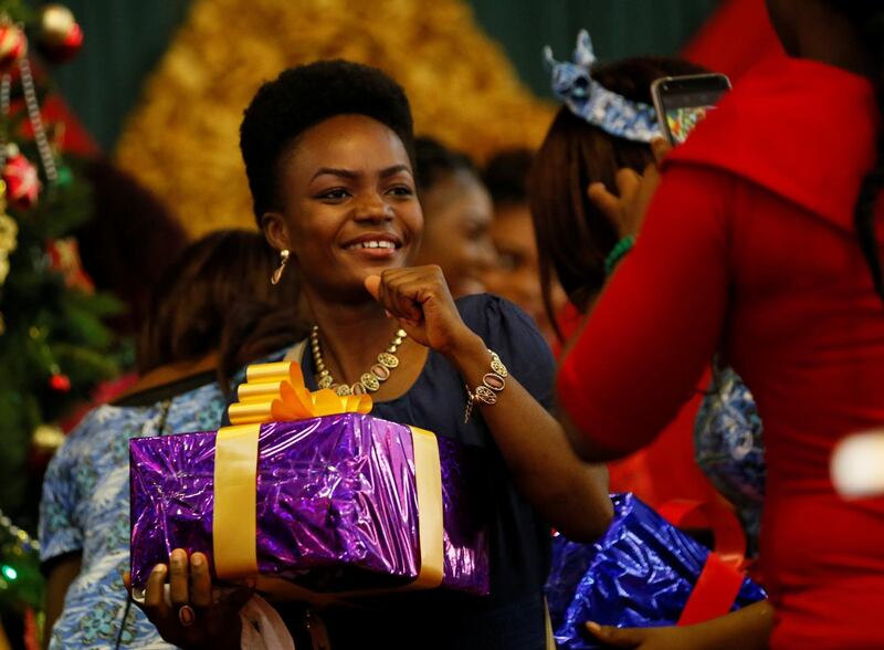 A lady takes a picture of a friend, holding a gift box, after the Christmas Day service at Living Faith Church Jahi in Abuja, Nigeria. REUTERS/Afolabi Sotunde