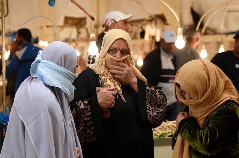 Tunisian women, covering their faces, walk past stalls in a central market in the capital Tunis on April 24, 2020, during the first day of the Muslim holy month of Ramadan, after authorities partially eased the lockdown measures. (Photo by FETHI BELAID / AFP)