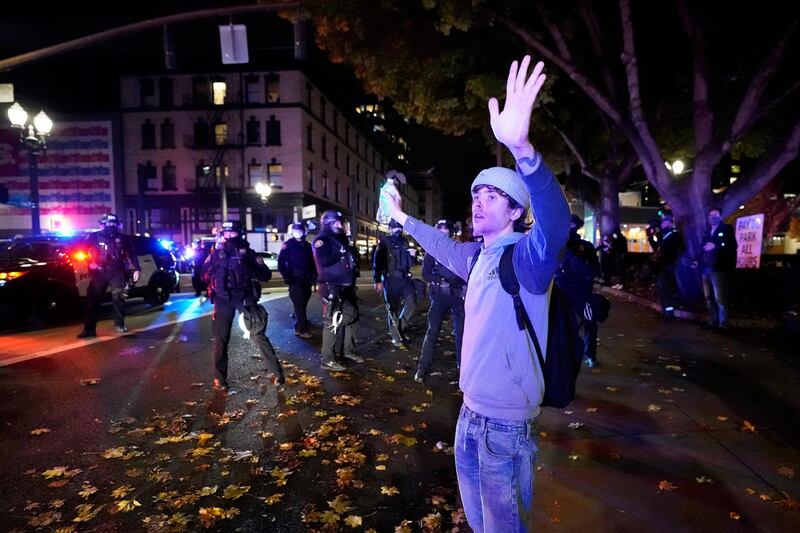 A man puts his arms up in front of police officers during protests in Portland, Oregon. AP Photo
