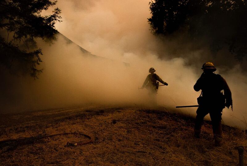 A firefighter walks through smoke as flames approach a home during the Mendocino Complex fire in Lakeport, California.  AFP PHOTO / JOSH EDELSON