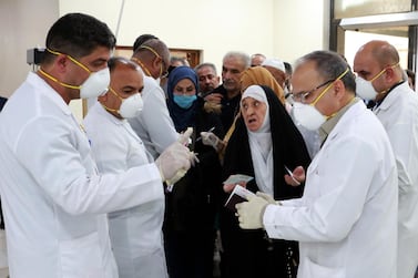 Members of Iraqi medical team check passengers upon arrival from Iran at Baghdad international airport on February 24, 2020. EPA