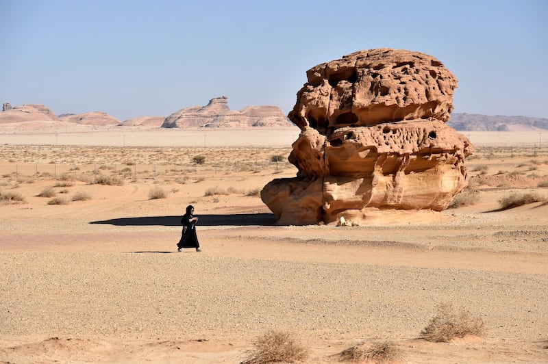 A picture taken on January 4, 2019, shows a woman walking past rose-coloured sandstone in Madain Saleh, a UNESCO World Heritage site, near Saudi Arabia's northwestern town of al-Ula. (Photo by Fayez Nureldine / AFP)