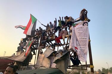 Protesters perched on a billboard frame at the sit-in outside the headquarters of Sudan's armed forces in Khartoum. Hamza Hendawi for The National