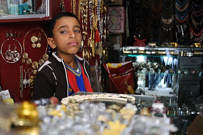 Ahmed Shahadi, 12, behind the counter of the jewelry shop he works for in the Old City of Sana'a. Photo: Lindsay Mackenzie for The National.