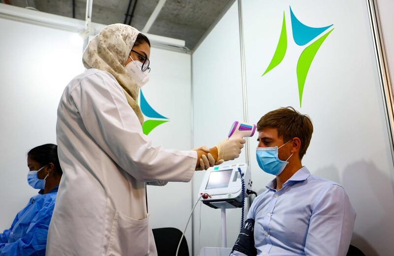 A health worker checks a man's temperature before he receives a dose of vaccine.  AFP