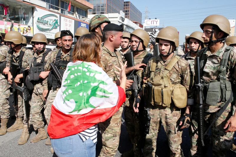 A demonstrator gestures as Lebanese army soldiers deploy to open a blocked road during ongoing anti-government protests in Zouk Mosbeh, Lebanon November 5, 2019. REUTERS/Mohamed Azakir