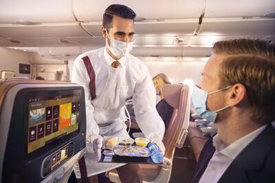 Masked Etihad flight personnel serve passengers. Etihad Airways