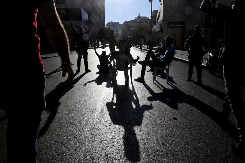 Protesters sit in chairs as they block a road leading to the Lebanese Parliament. EPA