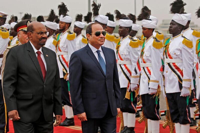 (FILES) In this file photo taken on October 25, 2018, Sudan's President Omar al-Bashir (L) inspects an honour guard with his Egyptian counterpart Abdel-Fattah al-Sisi (C) upon the latter's arrival at Khartoum International Airport outside the Sudanese capital. Sudanese leader Omar al-Bashir, long wanted on genocide and war crimes charges, was finally brought down in a popular uprising by the very people he ruled with an iron fist for 30 years. One of Africa's longest-serving presidents, the 75-year-old had remained defiant in the face of months-long protests that left dozens of demonstrators dead in clashes with security forces. / AFP / ASHRAF SHAZLY
