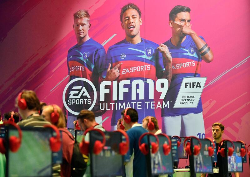 Visitors try out the latest FIFA 19 video game, promoted by a banner with soccer star Neymar, center, at the Gamescom fair for computer games in Cologne, Germany, Tuesday, Aug. 21, 2018. Hundreds of thousands gamers visit the leading European trade fair for digital gaming culture as the meeting point for global companies from the entertainment industry and the international gaming community. (AP Photo/Martin Meissner)