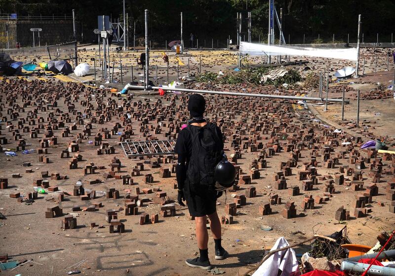 A protester stands near bricks placed on a road near Hong Kong Polytechnic University as a campaign of mass disruption in the semi-autonomous Chinese entered a fifth day on November 15, 2019. AP Photo