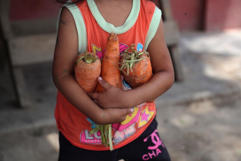 A child carries an armful of carrots to her mother who is helping prepare lunch at a soup kitchen in the Villa Maria slum of Lima, Peru, as the country battles a resurgence in Covid-19 cases. AP