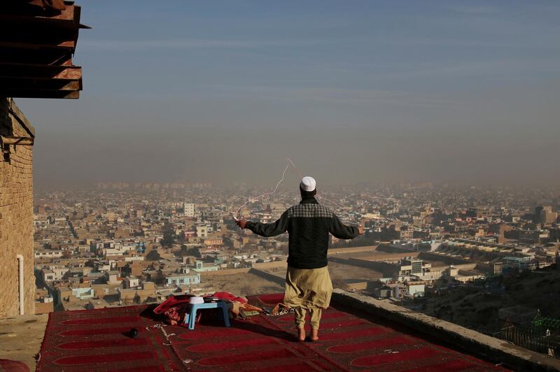 An Afghan boy skips on the rooftop of an Islamic seminary overlooking the Kabul skyline enveloped in smog in Afghanistan. AP Photo
