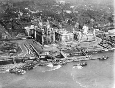George's Landing Stage and the Three Graces, Liverpool, Merseyside, 1920. A number of vessels plying their trade on the River Mersey. The 'Three Graces' are the Royal Liver Building (completed in 1911 with two clock towers crowned by mythical Liver Birds), the Cunard Building (completed in 1916) and the Port of Liverpool Building (completed in 1907). The landing stage at Pier Head served the transatlantic liner service. Artist Aerofilms. (Photo by English Heritage/Heritage Images/Getty Images)