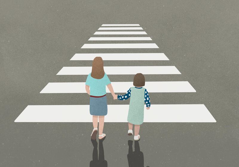 Woman and girl holding hands whilst walking through zebra crossing. Getty Images