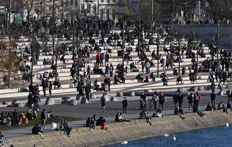 People sit on a bank of the Rhone River in Lyon, south-eastern France, before the start of a curfew. AFP