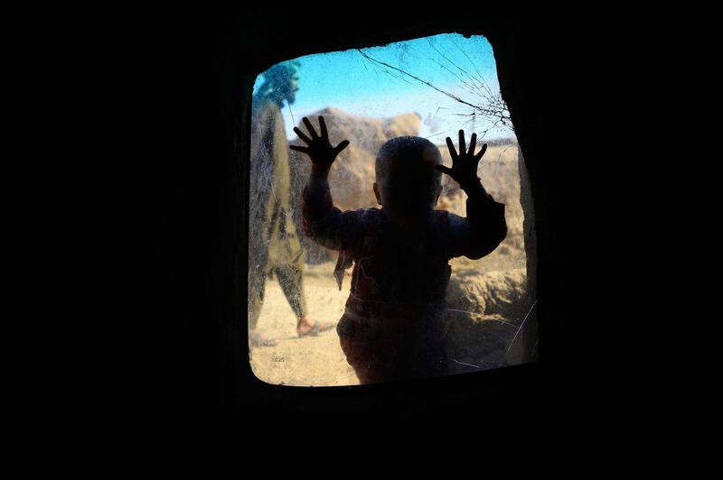 A child looks on from a windows in her temporary home at a refugee camp on the outskirts of Herat, Afghanistan. Hoshang Hashimi / AFP