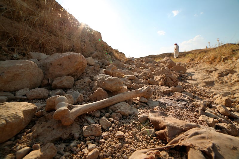 People visit a mass grave for the victims of the Islamic State group in Mosul, Iraq on Thursday, July 1, 2020. A human skull, a pair of worn trousers and a shoe were among the remains unearthed from a mass grave discovered this week in northern Iraq, a remnant of the brutal rule of the Islamic State group. (AP Photo/Farid Abdulwahed)