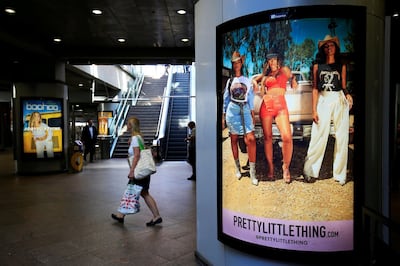A shopper walks pass advertising billboards for Boohoo and for 'Pretty Little Things', a Boohoo brand, at Canary Wharf DLR station in central London, Britain, September 17, 2018. REUTERS/James Akena