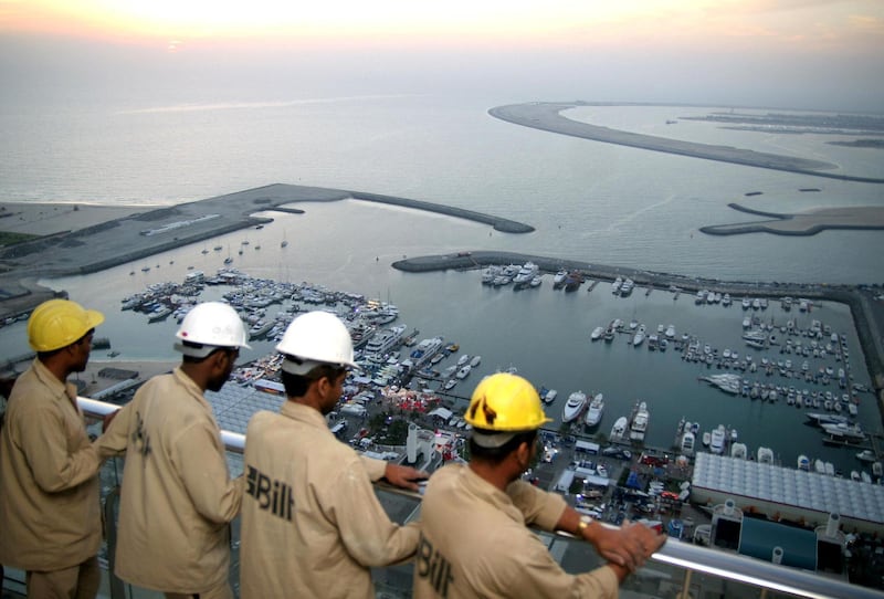 Indian workers watch the openning of Dubai's international boat show from the 50th floor of the tower which is beign constructed behind the Dubai International Marine Club, 14 March 2006. The governor of the UAE central bank sharply criticised yesterday the US Congress opposition to the acquisition of six US ports by Dubai Ports World (DPW) and called for a reassessment of US trade links. AFP PHOTO/ NASSER YOUNES / AFP PHOTO / NASSER YOUNES