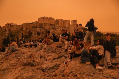 People stroll around the Acropolis area while African dust covers the sky of Athens. EPA