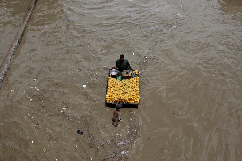 A fruit seller navigates a flooded road after heavy rainfall in Karachi. AP