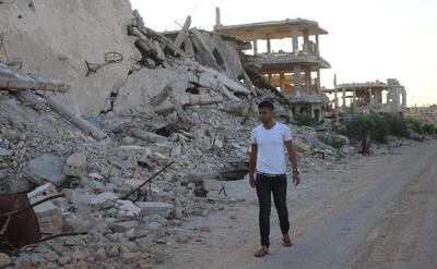 Moawiya Sayasina, the Syrian activist who started scribbling anti-Assad slogans in 2011, walks past the rubble of destroyed buildings in a rebel-held neighbourhood in the southern Syrian city of Daraa on June 5, 2018. "Your turn, Doctor." Seven years after scribbling the anti-Assad slogan that sparked Syria's war, activists-turned-rebels Moawiya and Samer Sayasina are bracing themselves for a regime assault on their hometown Daraa. / AFP / Mohamad ABAZEED
