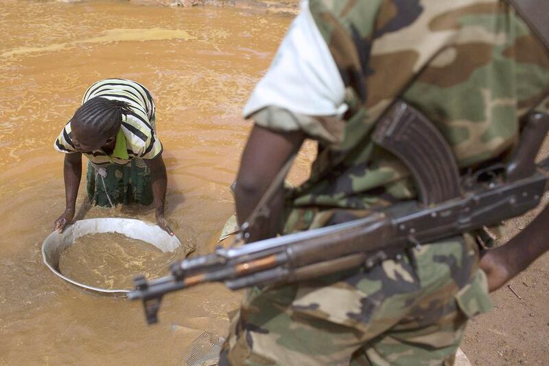 A former Seleka soldier looks at a woman washing extracted soil and small rocks as she pans for gold near an open-pit at the Ndassima gold mine near Djoubissi, north of Bambari. Siegfried Modola / Reuters