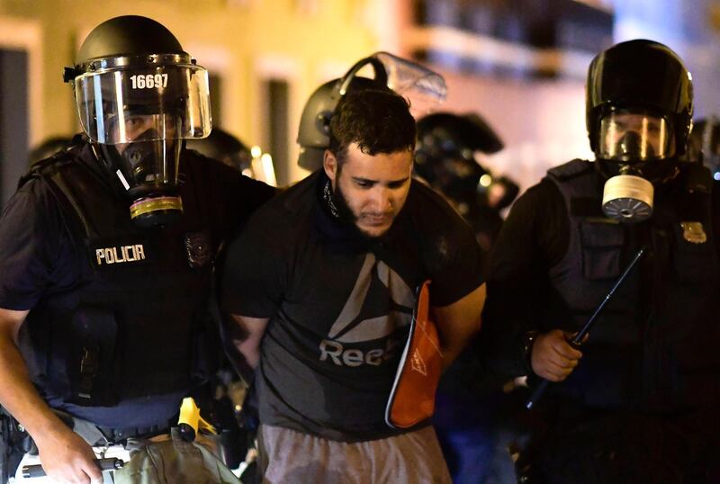 Police arrest a demonstrator during clashes demand the resignation of Gov. Ricardo Rossello in San Juan, Puerto Rico, Monday, July 22, 2019.  Protesters are demanding Gov. Ricardo Rossello step down following the leak of an offensive, obscenity-laden online chat between him and his advisers that triggered the crisis.   (AP Photo/Carlos Giusti)