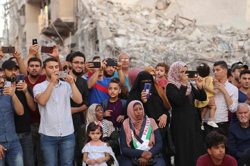 Palestinians in Gaza listen to the Music Among the Rubble concert in front of the remains of Al Shuruq Tower, which was levelled by an Israeli air strike. AFP