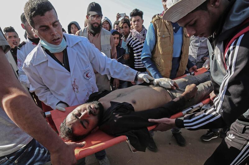 Medical staff carry an injured Palestinian man at an emergency medical tent after clashes with Israeli security forces after a demonstration near the border with Israel, east of Khan Yunis, in the southern Gaza Strip, on April 01, 2018. / AFP PHOTO / SAID KHATIB