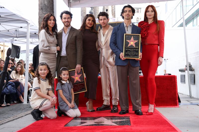 The Jonas Brothers pose with their wives and children during their star unveiling ceremony. Reuters