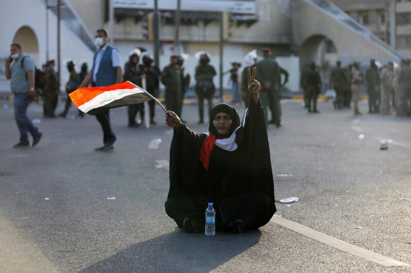A woman holding the Iraqi flag gestures while siting on the street as demonstrators take part in an anti-government protest in Baghdad, Iraq May 25, 2021. REUTERS/Thaier Al-Sudani