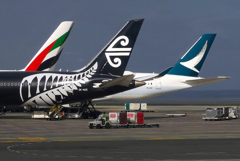 FILE PHOTO - A worker drives a vehicle across the tarmac past aircraft bearing the logos of Emirates, Air New Zealand and Cathay Pacific airlines at Auckland Airport in New Zealand, June 25, 2017.     REUTERS/David Gray/File Photo