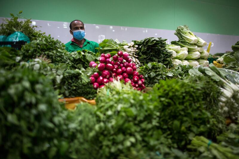 A seller wearing a protective mask at the vegetables market in Dubai. The Dubai authorities reopened some fish, meat and vegetables markets to the public after they were closed weeks ago to limit spread of the covid-19 coronavirus.  EPA