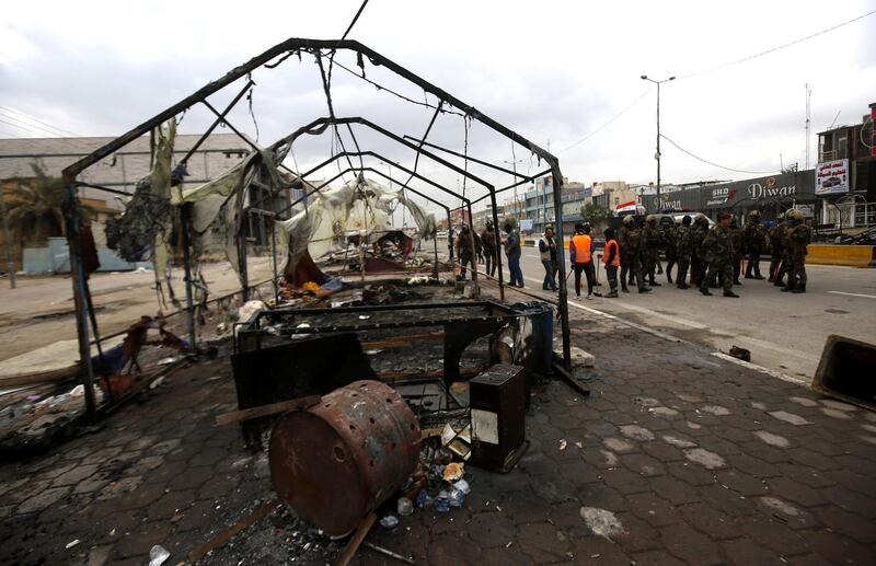 Iraqi soldiers inspect the wreckage of protesters' tents at the protest site in Basra.  EPA